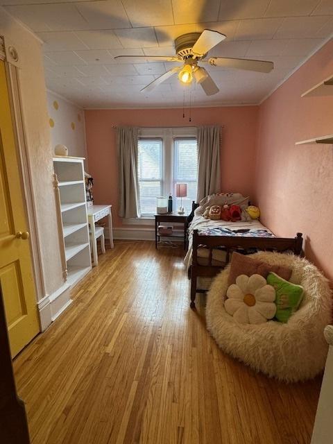 bedroom featuring ceiling fan, ornamental molding, and hardwood / wood-style flooring