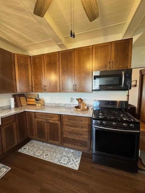 kitchen with stainless steel gas range oven, beamed ceiling, and dark hardwood / wood-style floors