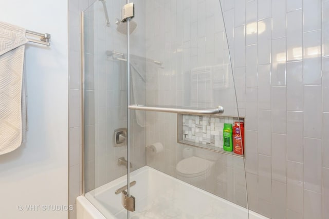 bathroom with bath / shower combo with glass door and toilet