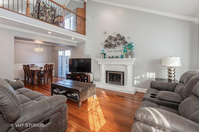 living room with crown molding, a towering ceiling, and hardwood / wood-style floors