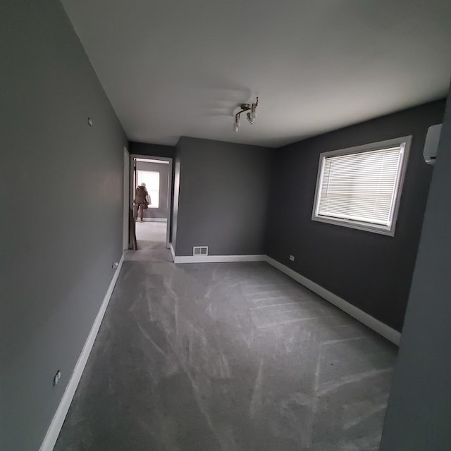 carpeted empty room featuring a wall mounted AC