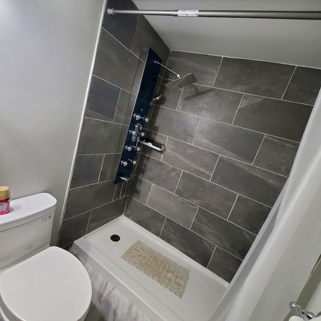 bathroom with a tile shower and toilet