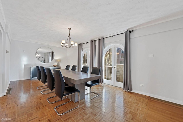 dining space with light parquet flooring, a notable chandelier, a textured ceiling, and french doors