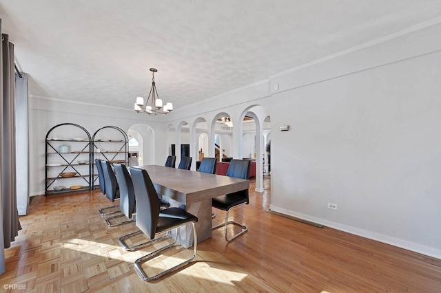 dining area featuring crown molding, light wood-type flooring, a notable chandelier, and a textured ceiling