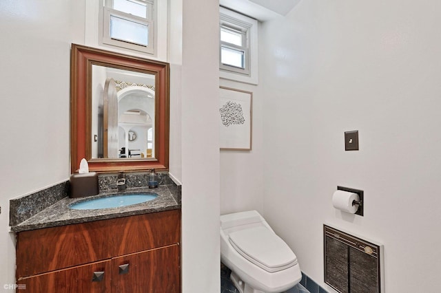 bathroom featuring vanity, heating unit, and toilet