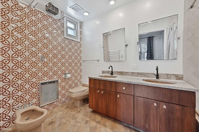 bathroom with a bidet, vanity, heating unit, and toilet