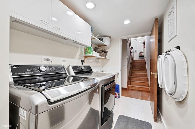 laundry area featuring cabinets, light tile patterned floors, and washing machine and clothes dryer