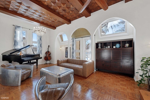 living room with parquet flooring, a towering ceiling, a chandelier, and beam ceiling