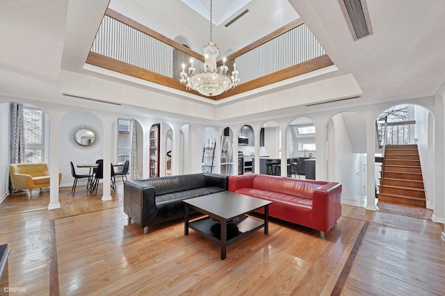 living room featuring a notable chandelier, a tray ceiling, and light hardwood / wood-style flooring