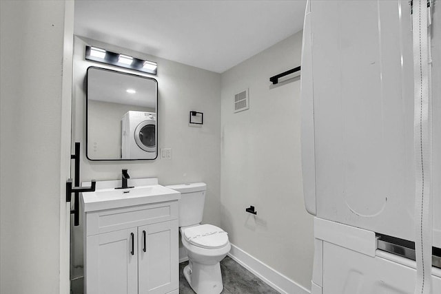 bathroom with vanity, toilet, and stacked washer and dryer