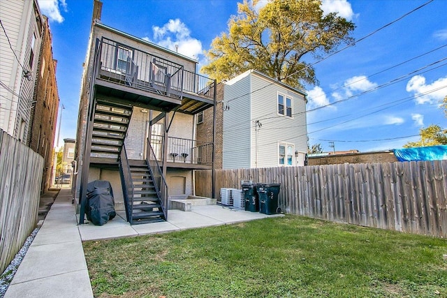 back of property featuring a balcony, cooling unit, a patio area, and a lawn