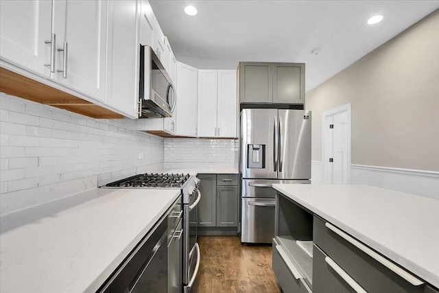 kitchen featuring decorative backsplash, dark hardwood / wood-style flooring, gray cabinetry, stainless steel appliances, and white cabinets