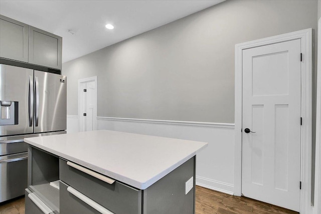 kitchen with stainless steel fridge, a center island, dark wood-type flooring, and gray cabinetry