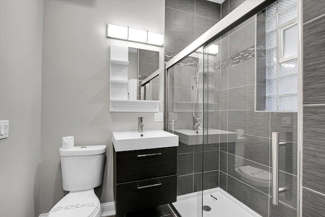 bathroom featuring vanity, toilet, and a shower with door