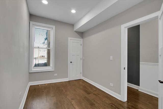 empty room featuring plenty of natural light and dark wood-type flooring