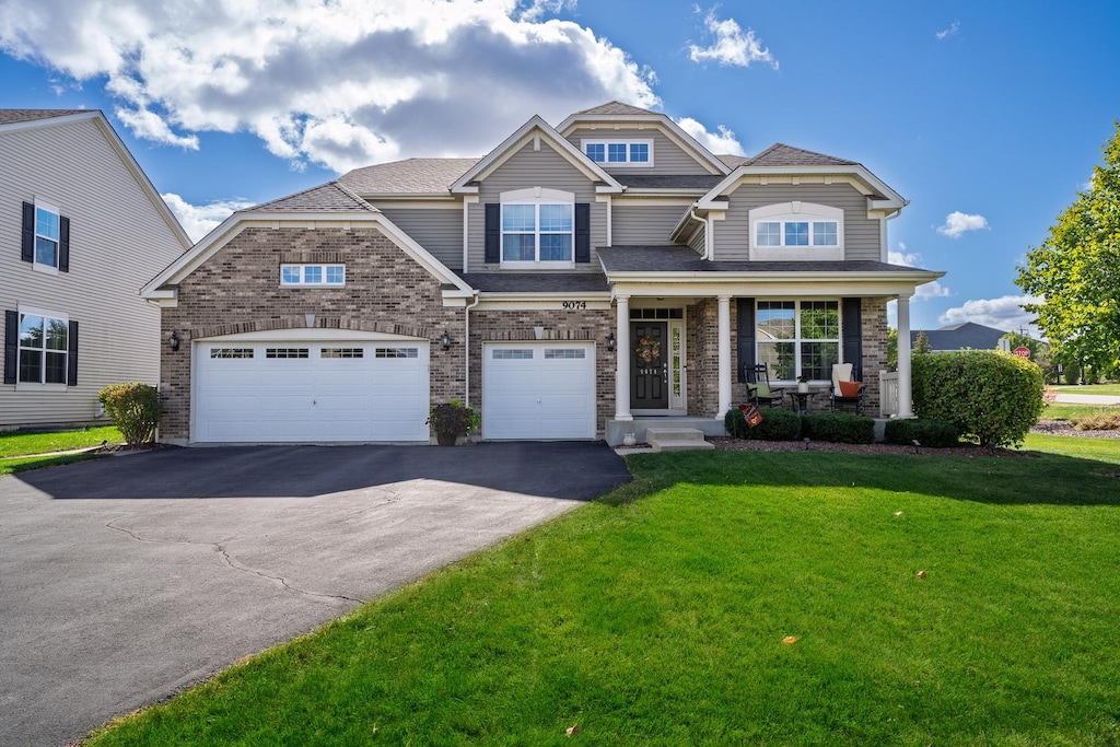 craftsman inspired home with covered porch, a front yard, and a garage