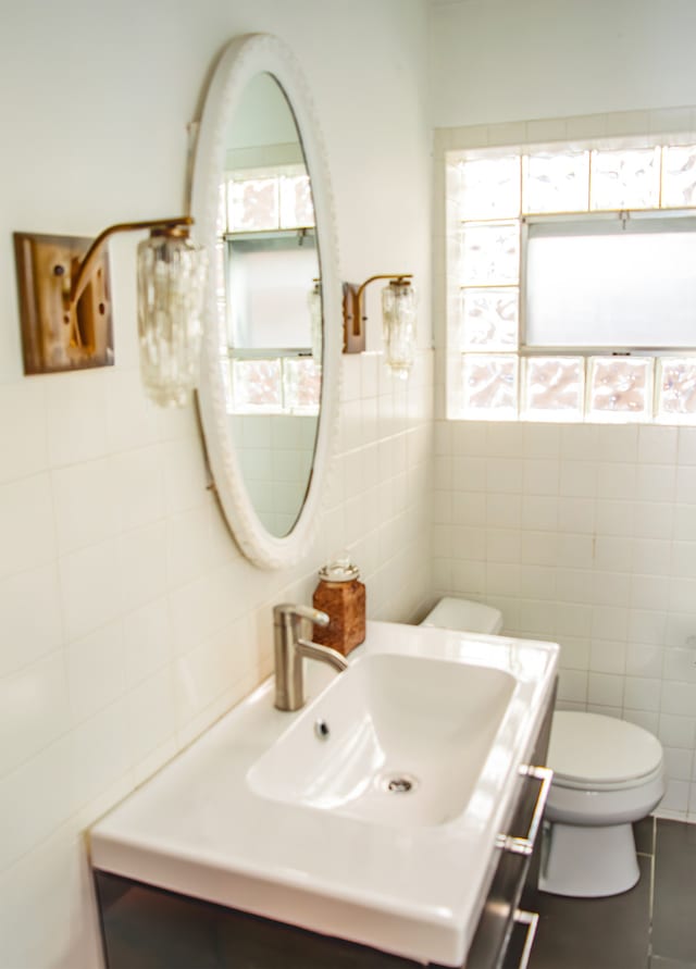 bathroom featuring tile patterned flooring, vanity, tile walls, and toilet