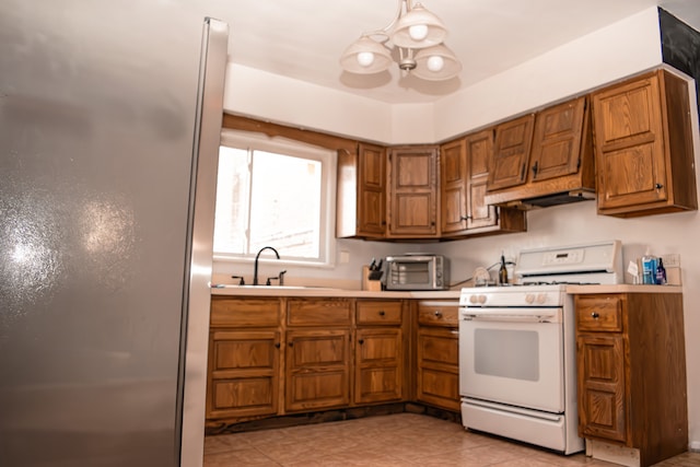 kitchen featuring custom exhaust hood, sink, pendant lighting, white stove, and stainless steel refrigerator