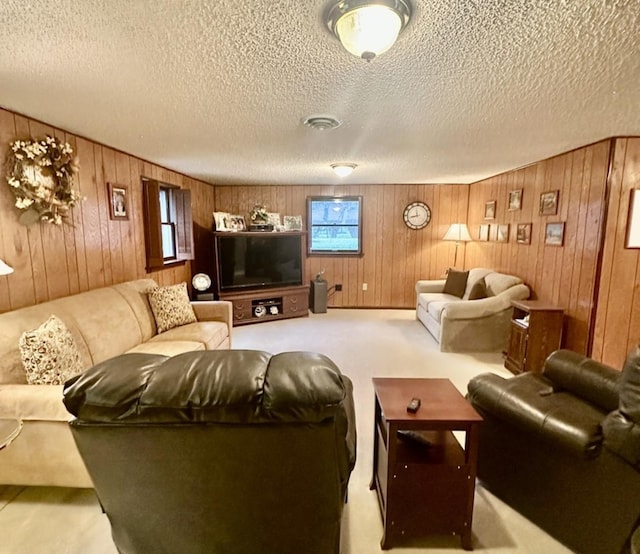 living room with wood walls, light colored carpet, and a textured ceiling