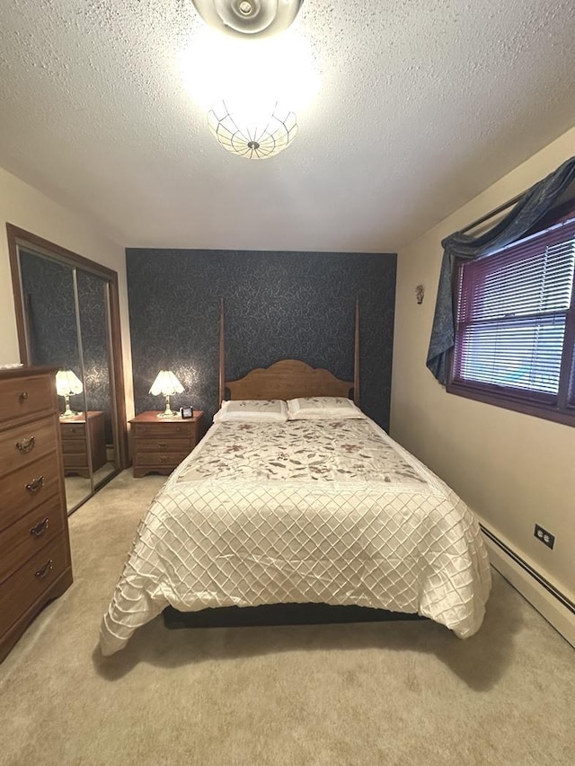 carpeted bedroom with a textured ceiling and a baseboard heating unit