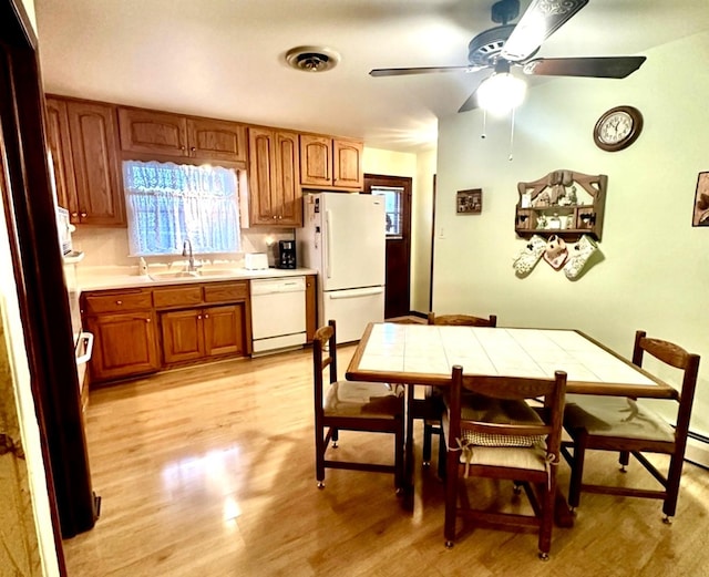 kitchen with light wood-type flooring, white appliances, ceiling fan, sink, and tile counters