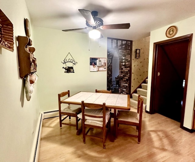 dining space featuring ceiling fan, a baseboard radiator, and light wood-type flooring