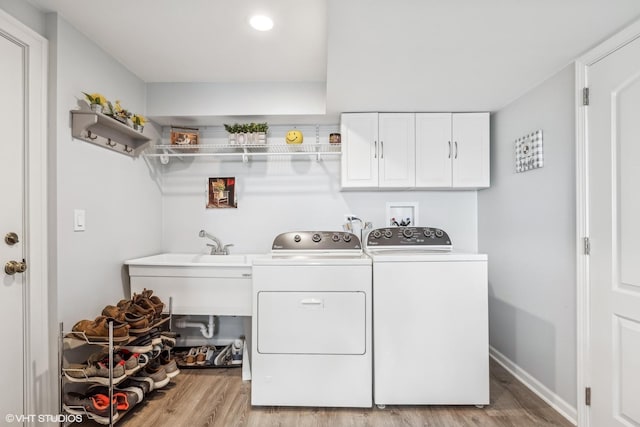 washroom featuring washer and clothes dryer, cabinets, and light wood-type flooring