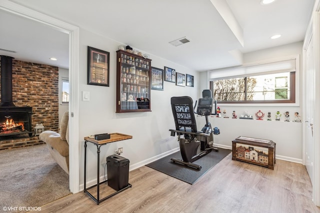 exercise area with a wood stove and light hardwood / wood-style flooring