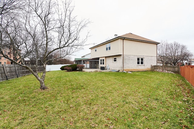 rear view of property featuring brick siding, a fenced backyard, a lawn, and a sunroom