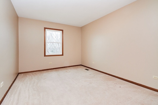 empty room featuring light colored carpet and baseboards