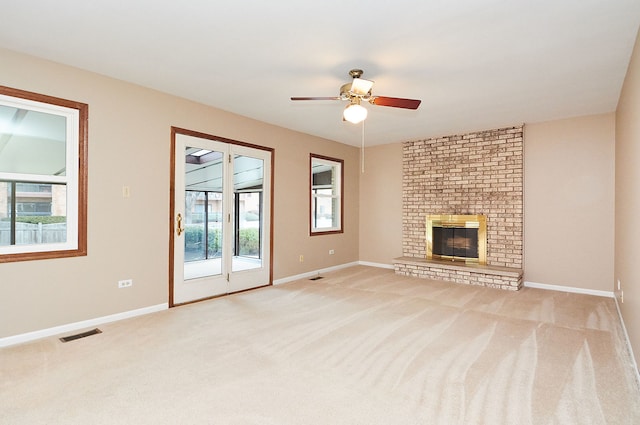 unfurnished living room featuring carpet, visible vents, baseboards, ceiling fan, and a brick fireplace