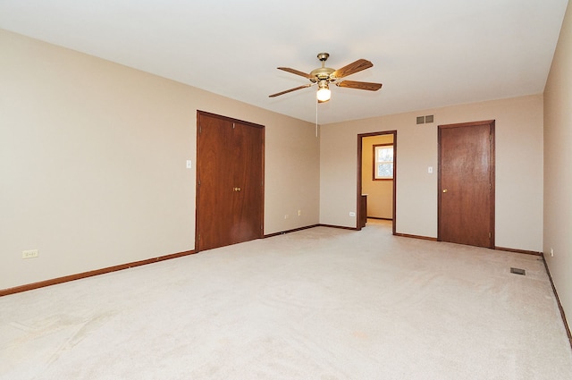 empty room featuring visible vents, baseboards, light carpet, and ceiling fan