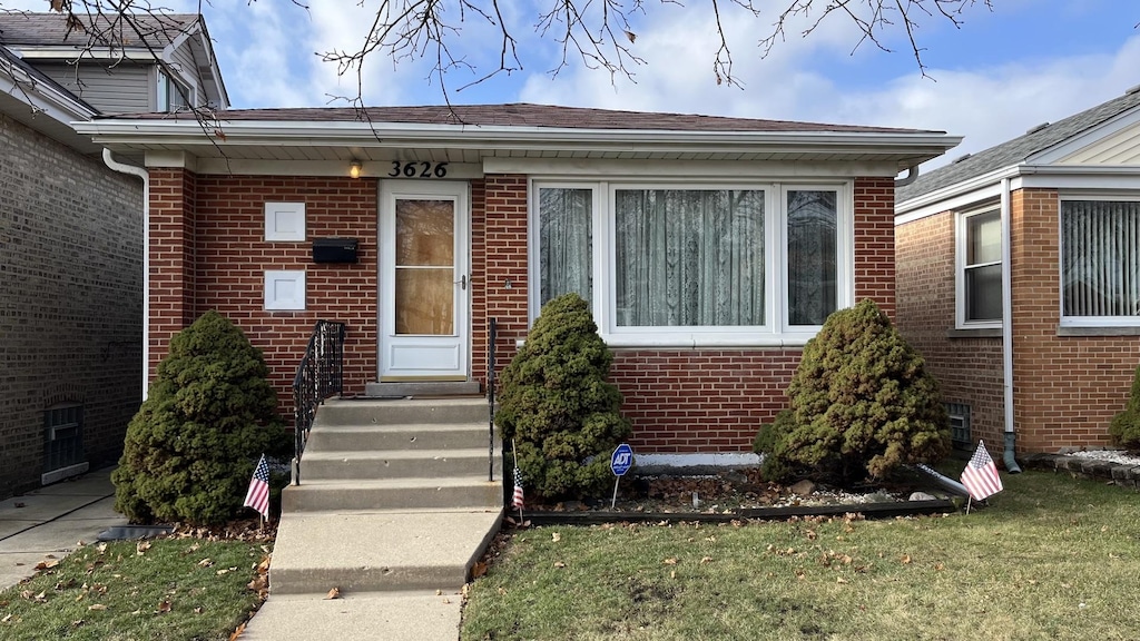 entrance to property with a lawn and brick siding