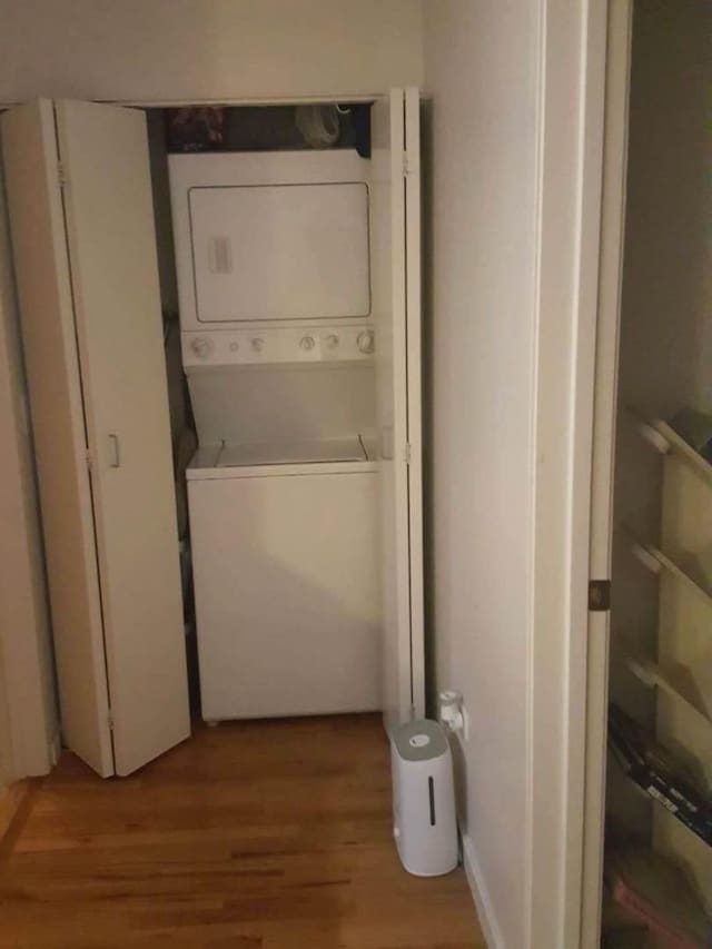 laundry area with stacked washer and dryer and light hardwood / wood-style flooring