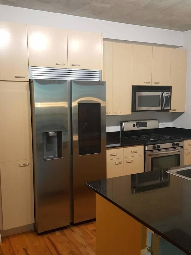 kitchen with cream cabinetry, light hardwood / wood-style floors, and appliances with stainless steel finishes