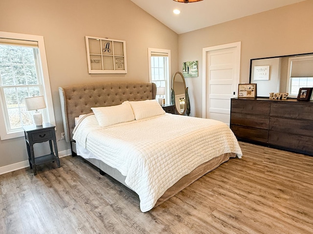 bedroom featuring wood-type flooring, vaulted ceiling, and multiple windows