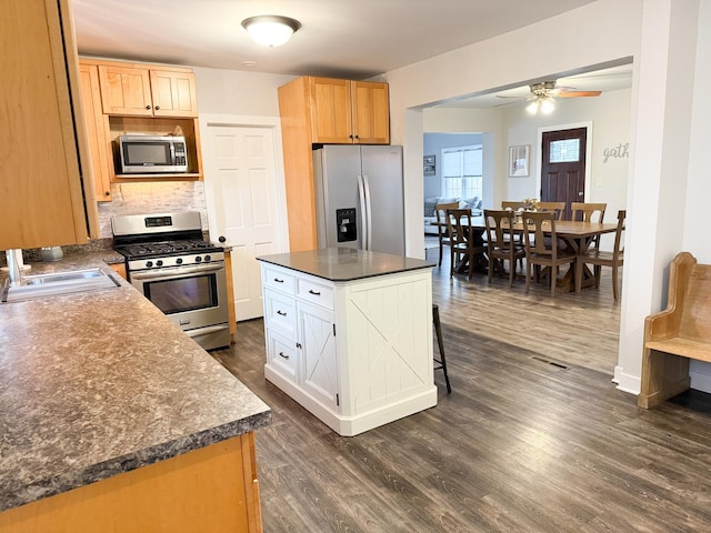 kitchen with sink, dark wood-type flooring, appliances with stainless steel finishes, a center island, and white cabinets