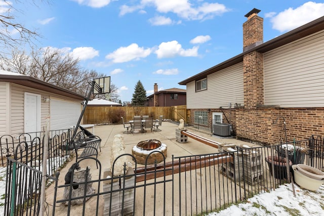 snow covered patio with central AC and a fire pit