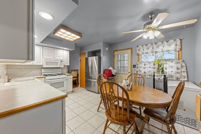 kitchen with white appliances, white cabinets, sink, ceiling fan, and light tile patterned flooring