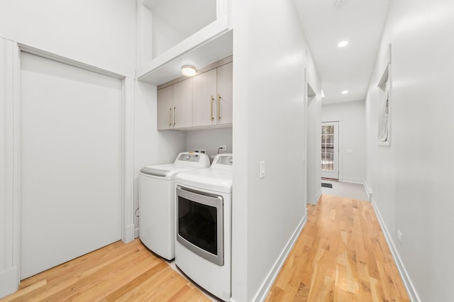 washroom featuring light hardwood / wood-style floors, cabinets, and washing machine and clothes dryer