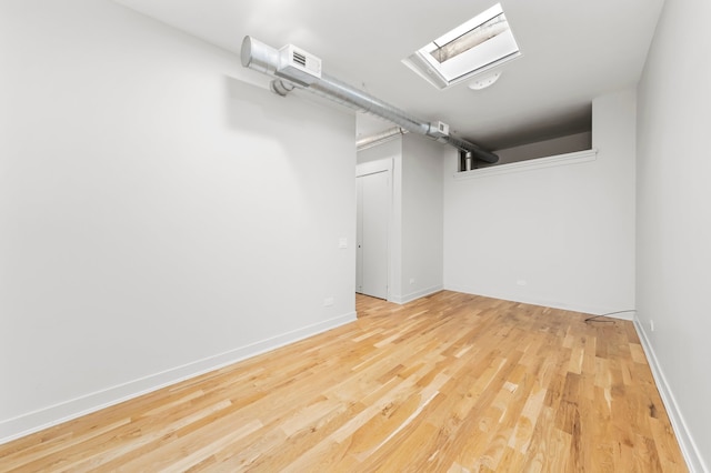 empty room with light wood-type flooring and a skylight