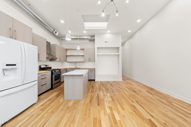 kitchen with sink, light hardwood / wood-style flooring, wall chimney exhaust hood, stainless steel gas stove, and white fridge with ice dispenser