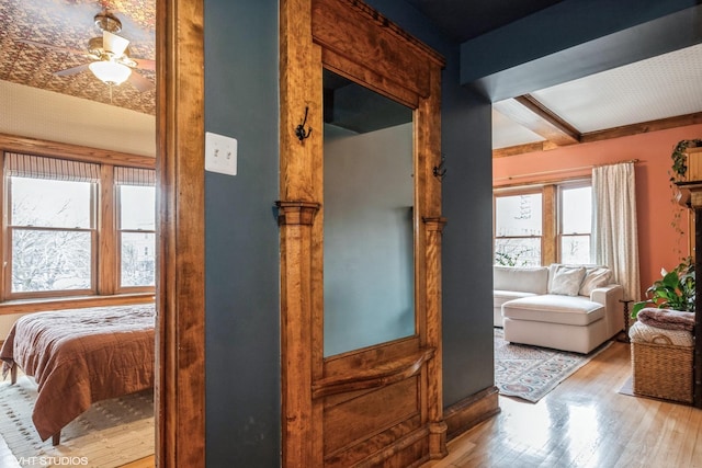 corridor with beamed ceiling and light hardwood / wood-style flooring