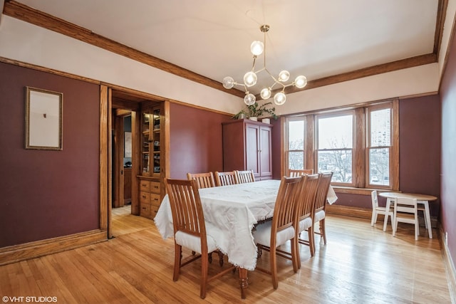 dining space with light hardwood / wood-style floors, a notable chandelier, and crown molding