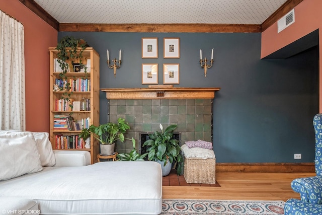 living room featuring ornamental molding, a tile fireplace, and wood-type flooring