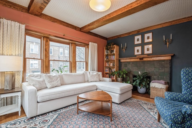 living room with a fireplace, beamed ceiling, and wood-type flooring