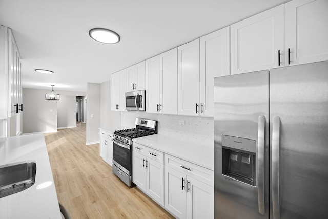 kitchen with sink, stainless steel appliances, white cabinetry, and light hardwood / wood-style flooring