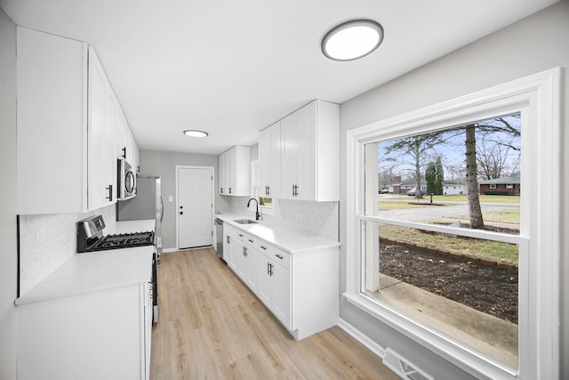 kitchen with backsplash, stainless steel appliances, white cabinetry, and sink