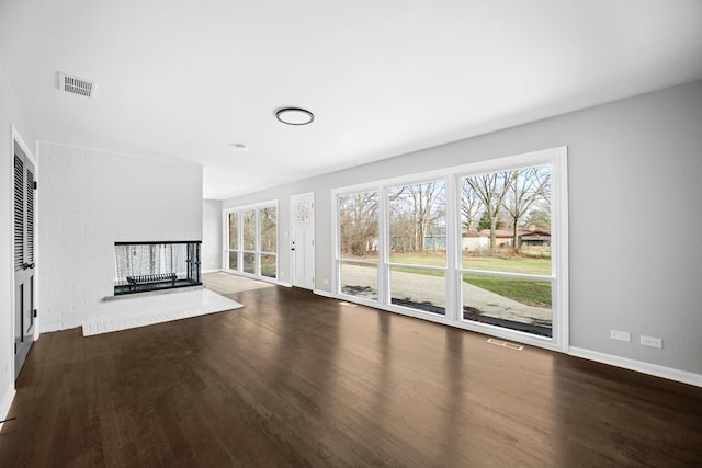 unfurnished living room with dark hardwood / wood-style flooring and a brick fireplace