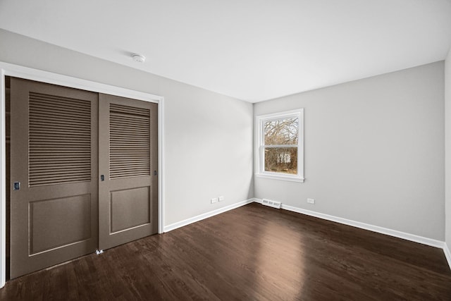 unfurnished bedroom with a closet and dark wood-type flooring